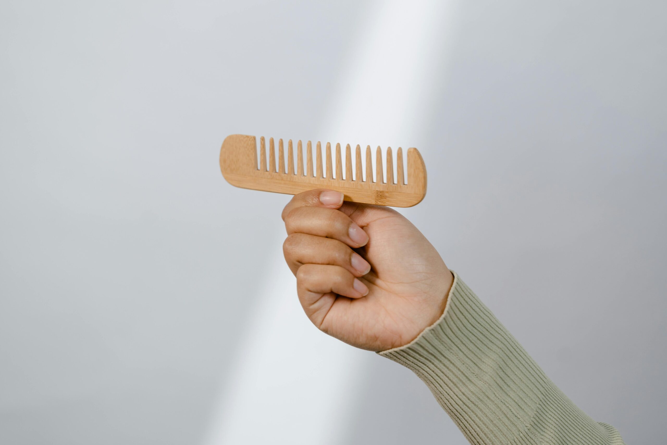 A Person Holding a Wooden Comb A Person Holding a Wooden Comb